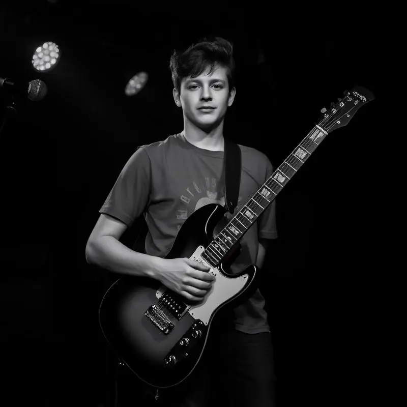 Retrato en blanco y negro de un músico con guitarra eléctrica en un escenario